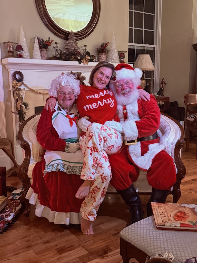 woman sitting with Santa and Mrs Claus during a fun Christmas weekend getaway for women