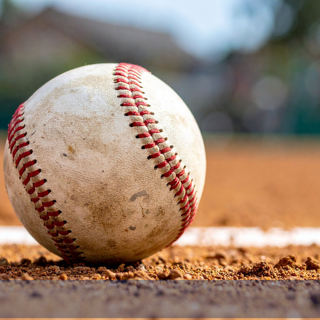 A baseball on the dirt in a field.